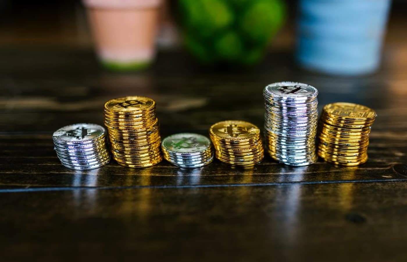Stacks of coins of increasing height on a dark table.