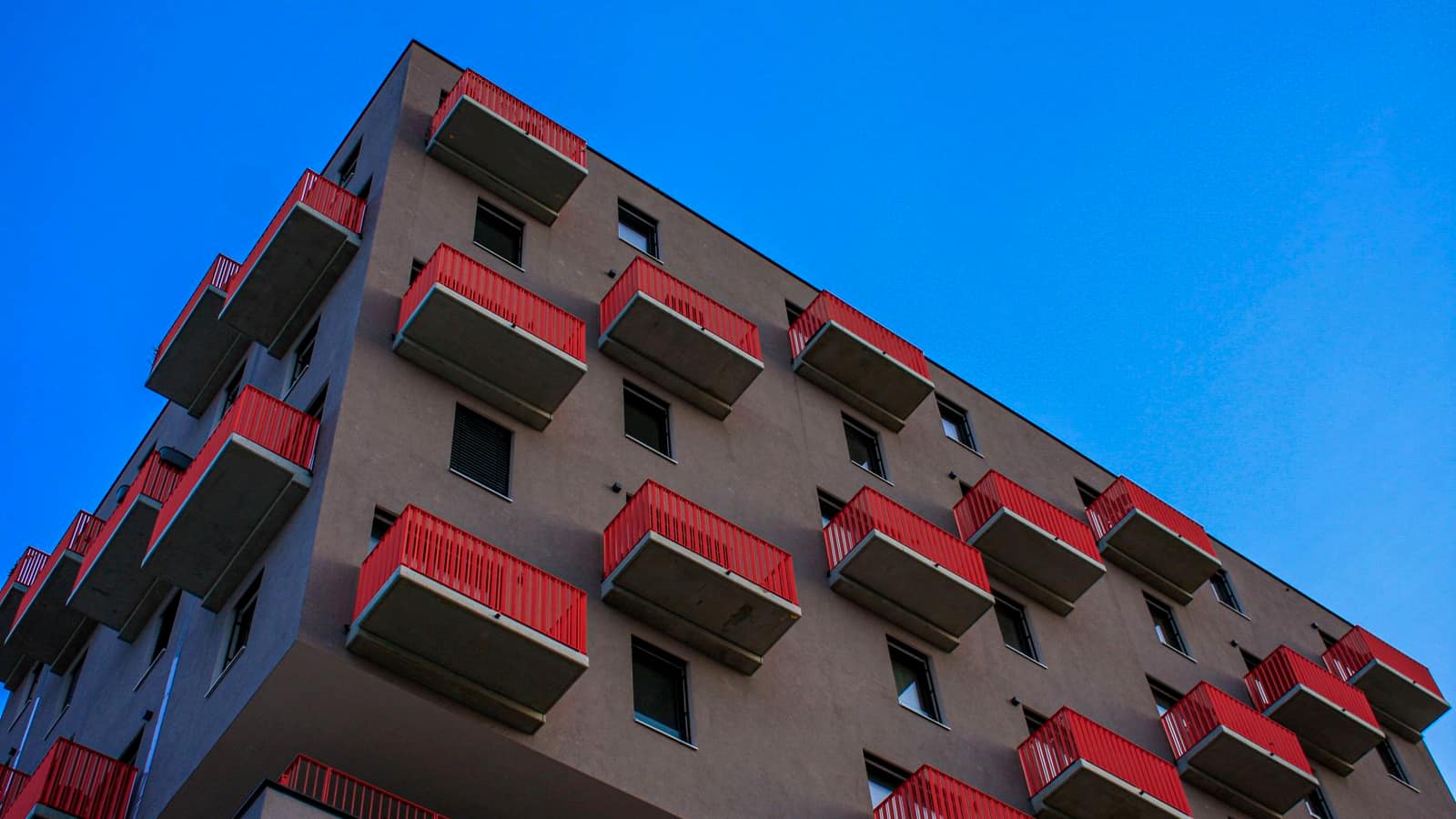 A modern apartment building with rows of balconies against a blue sky
