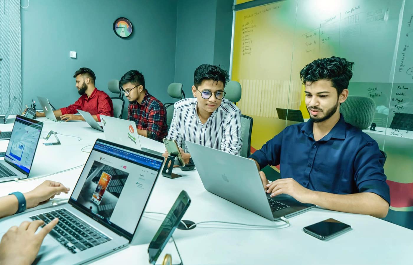A group of people working on laptops at a long table in a coworking office