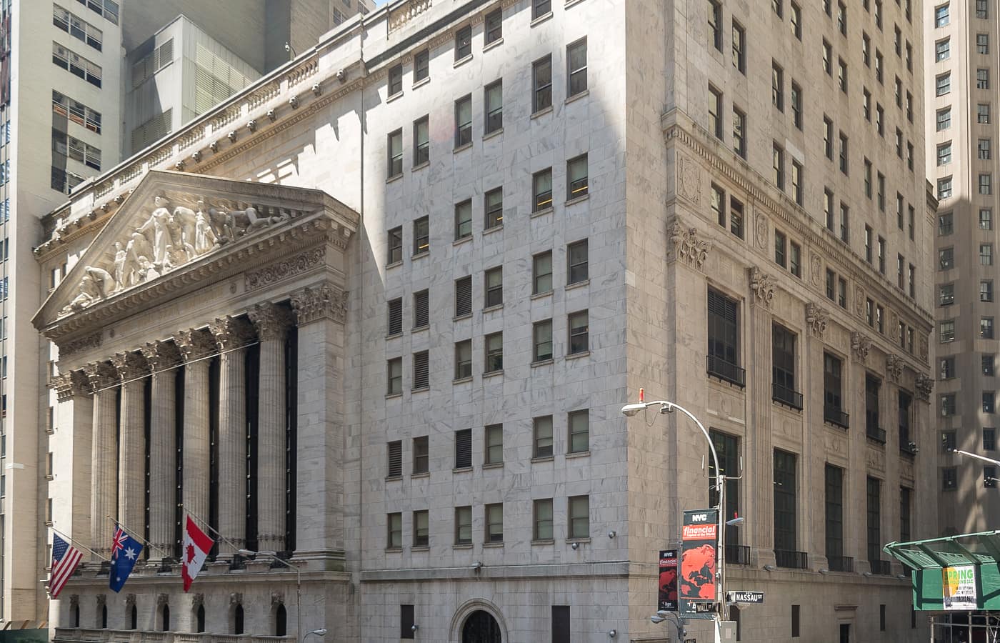 The columned facade of the New York Stock Exchange building with a large American flag